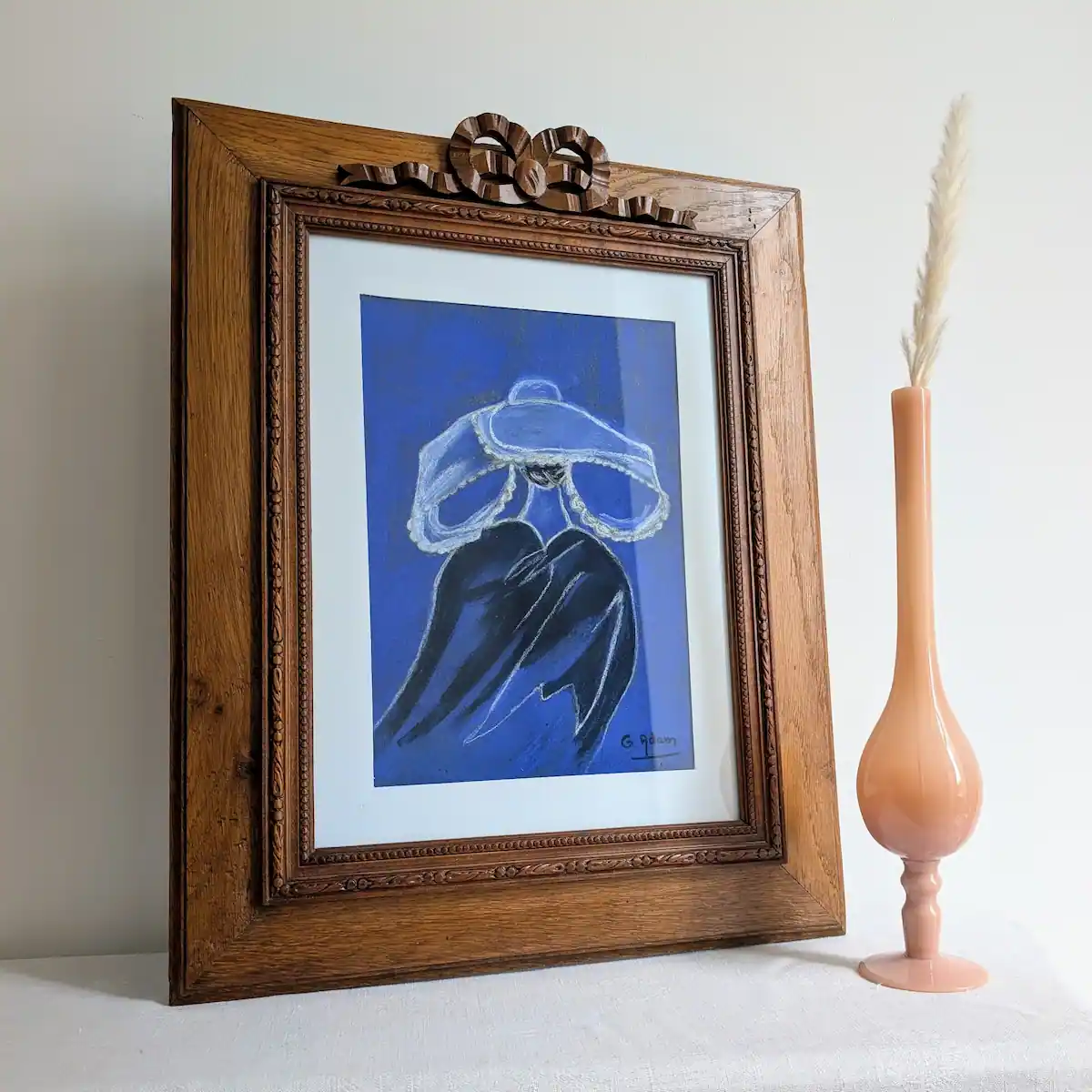 Cadre en chêne Louis XVI et son pastel breton bleu mis en situation sur une table à côté d'un vase.