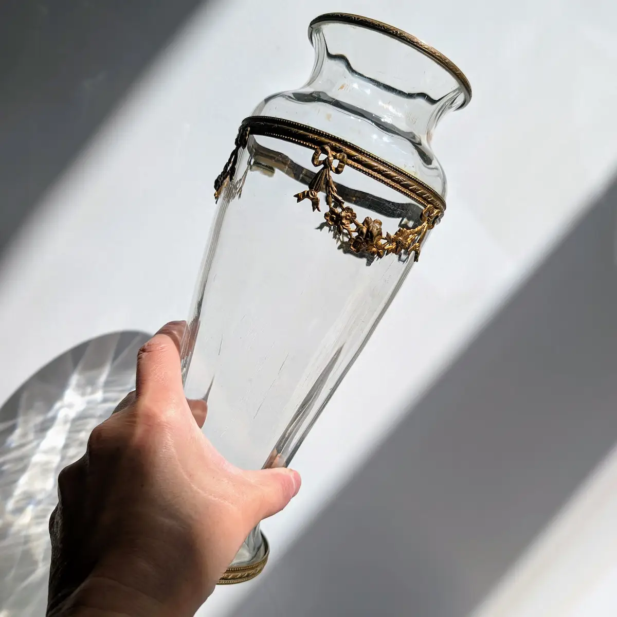 Vase ancien en verre soufflé tenu en main montrant ses proportions