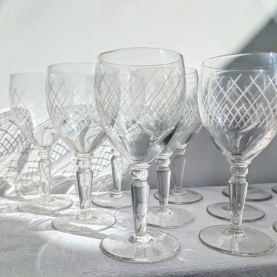 Verres à vin en cristalin gravé projetant des ombres de croisillons sur la table