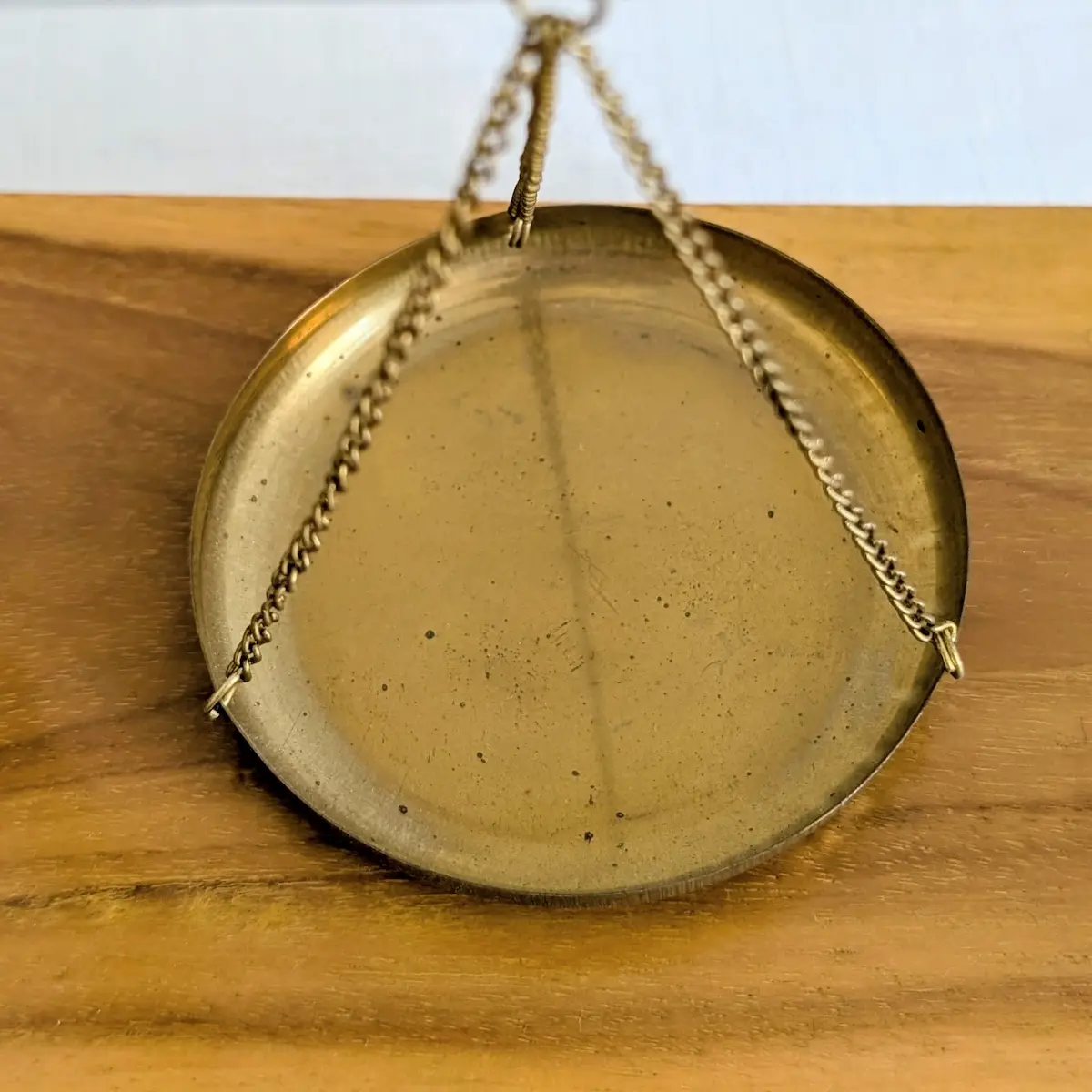 Gros plan sur un plateau circulaire suspendu en laiton d'une balance ancienne