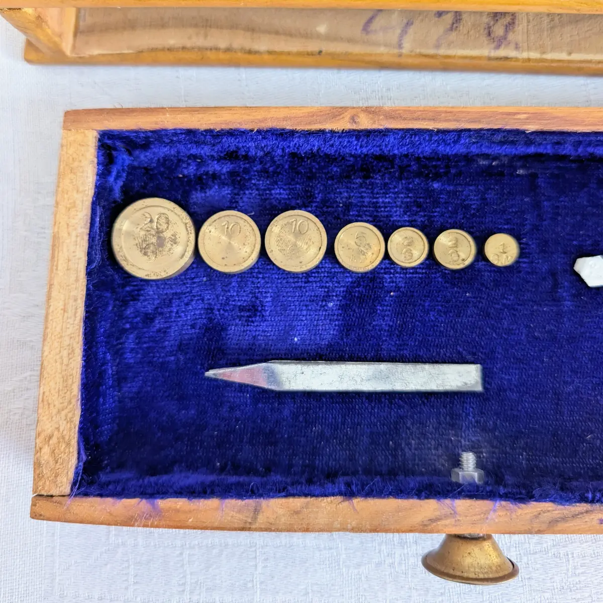Jeu de poids gradués anciens et pince de manipulation en métal