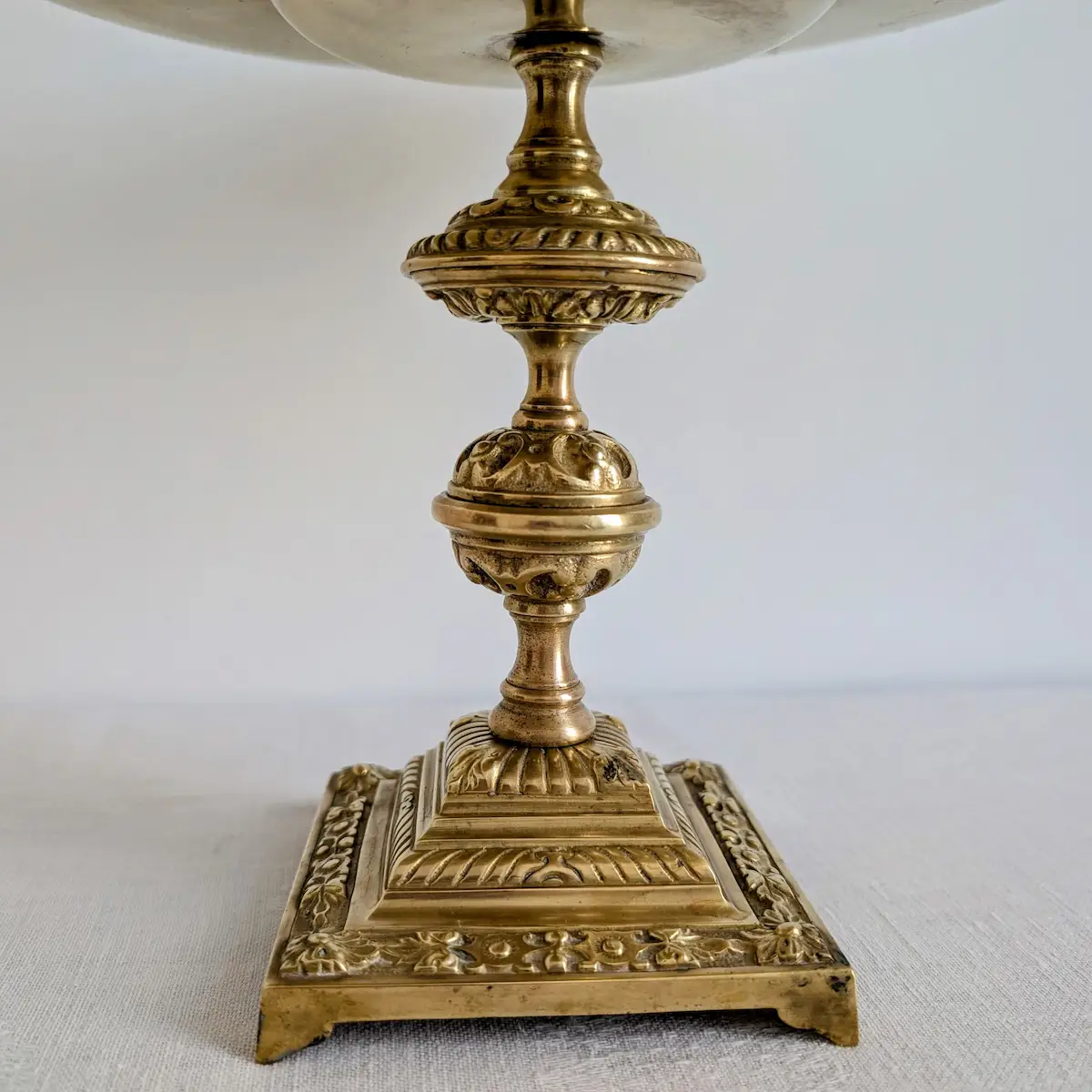 Détail du socle carré ciselé et du pied mouluré du bougeoir en laiton