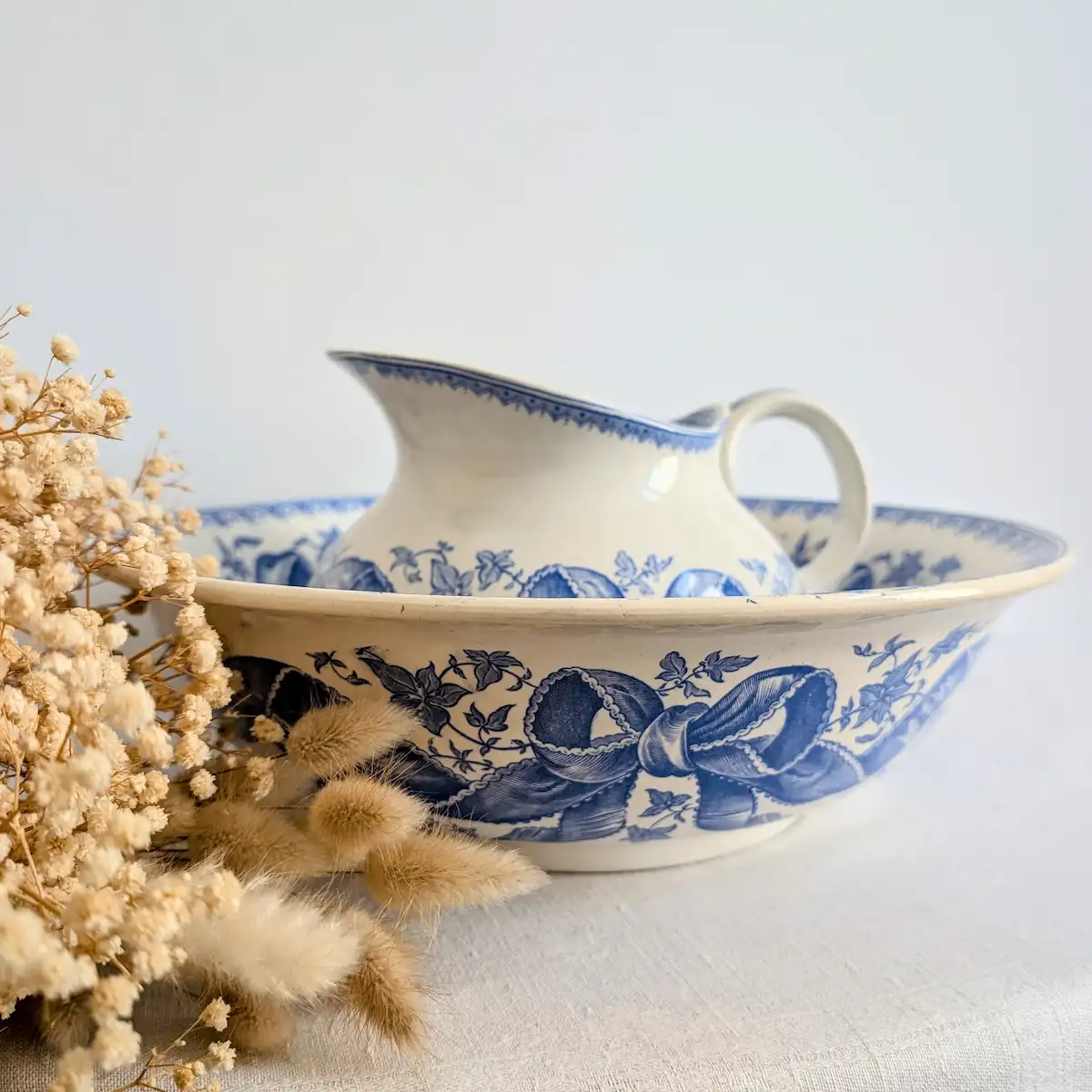Mise en scène d'un broc et d'une bassine anciens Sarreguemines avec des fleurs séchées.