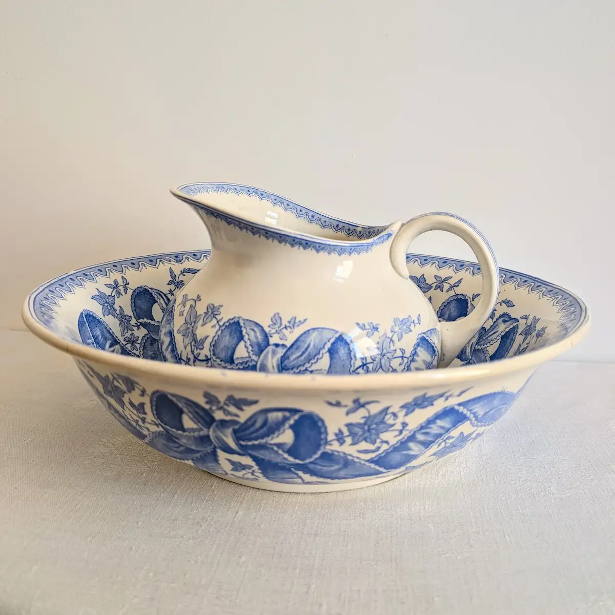 Ensemble de toilette ancien Sarreguemines modèle Rosette avec broc et bassine en faïence bleue.