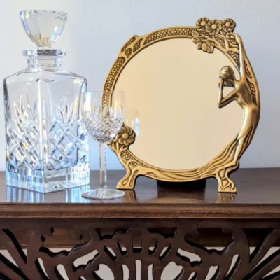 Miroir à poser Art nouveau en laiton présenté sur une console ancienne aux côtés d'objets en cristal
