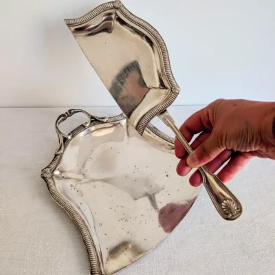 Présentation de la pelle à miettes ancienne au-dessus de son plateau en métal argenté
