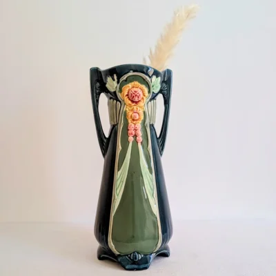 Vase Art nouveau en céramique garni d'une plume décorative sur fond neutre