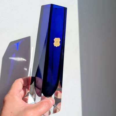 Présentation en main d'un vase moderniste en cristal bleu Wasungen contre jour