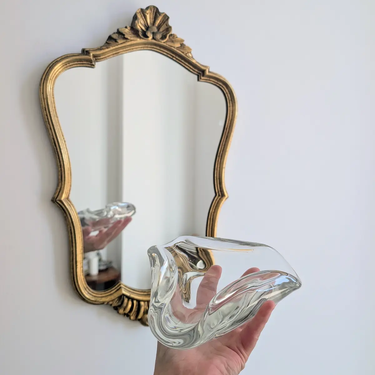 Vide-poche Baccarat tenu en main devant un miroir doré