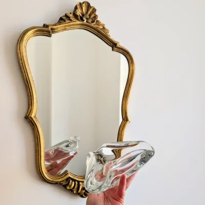 Vide-poche Baccarat tenu en main devant miroir doré angle bas