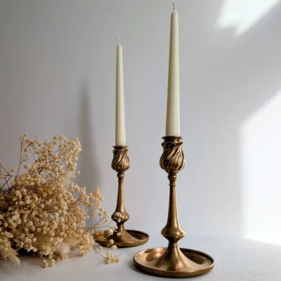 Bougeoirs 1900 en laiton torsadé allumés à côté d'un bouquet de fleurs séchées