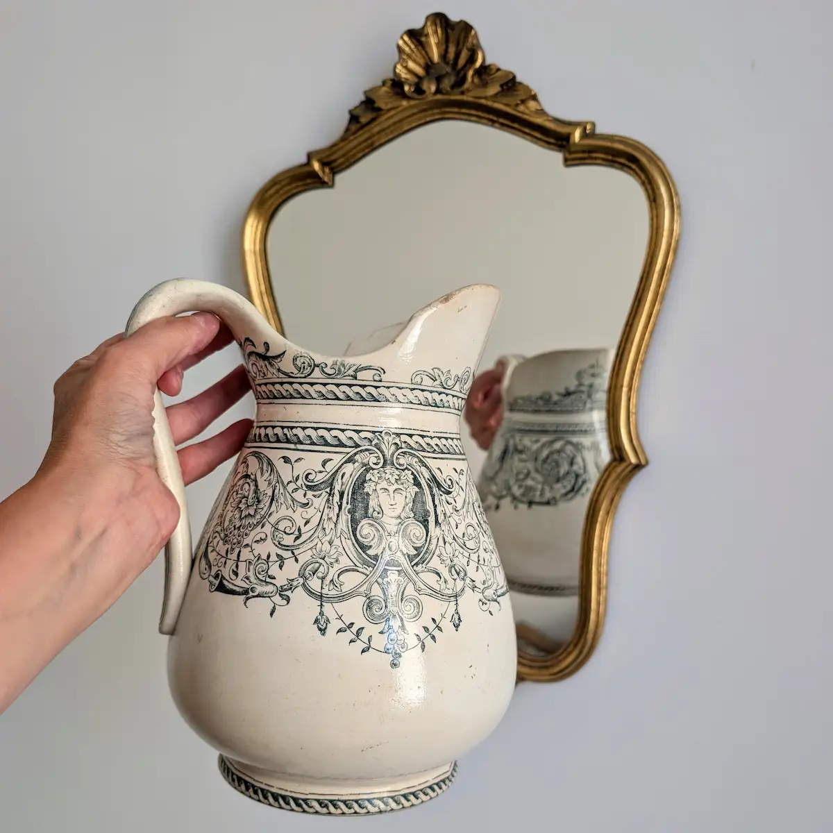 Prise en main du broc de toilette ancien en faïence pour visualiser l échelle