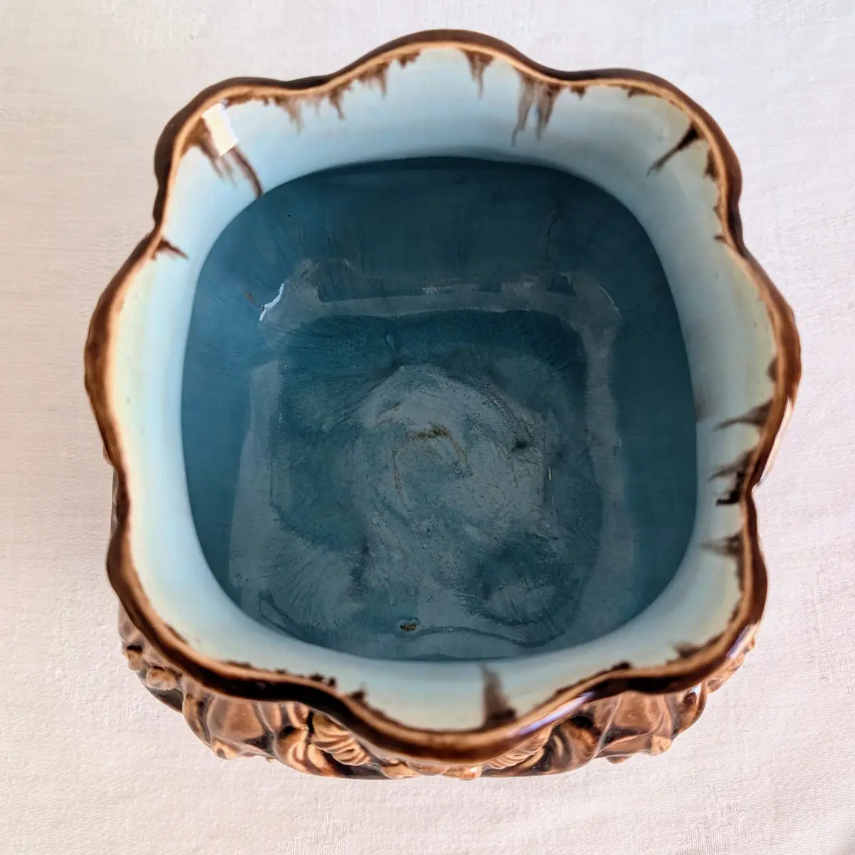 Vue plongeante sur l'intérieur émaillé bleu céladon d'un cache-pot ancien en barbotine.