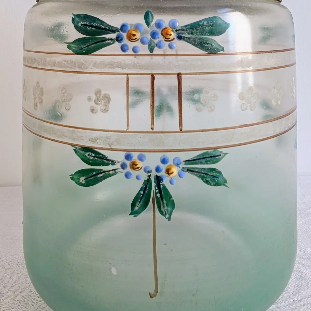 Gros plan sur les fleurs émaillées bleues et dorées peintes sur verre vert d'eau