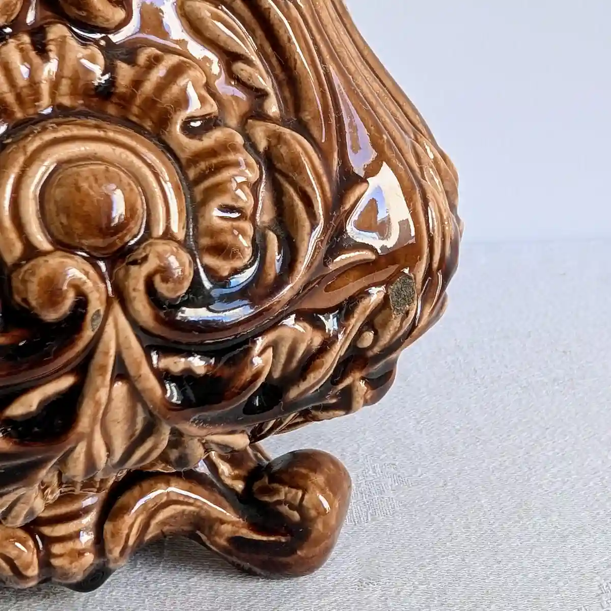 Gros plan sur les décors en fort relief et la patine de l'émail brun d'un cache-pot en barbotine.