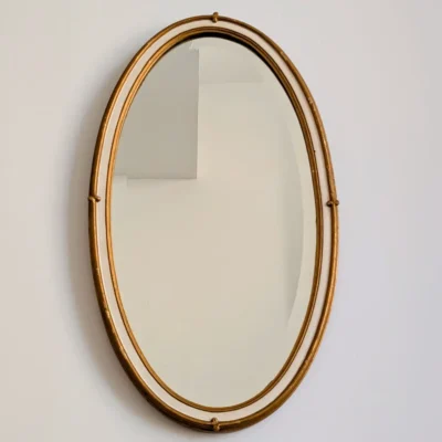 Vue de face miroir ancien ovale de coiffeuse cadre mouleré doré et blanc patiné