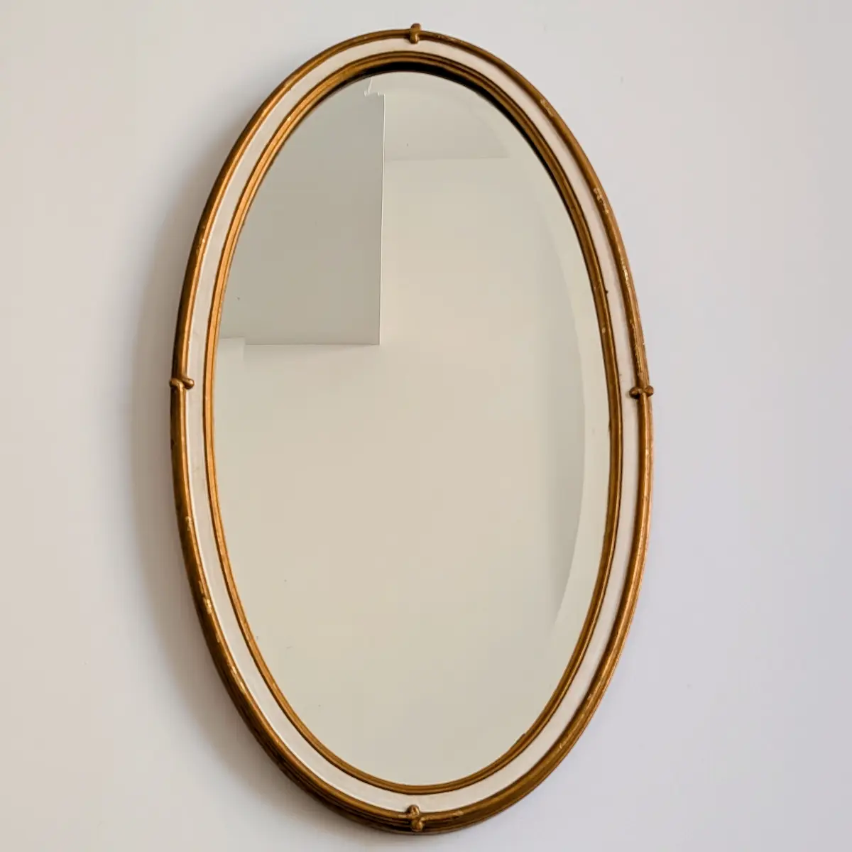 Vue de face miroir ancien ovale de coiffeuse cadre mouleré doré et blanc patiné