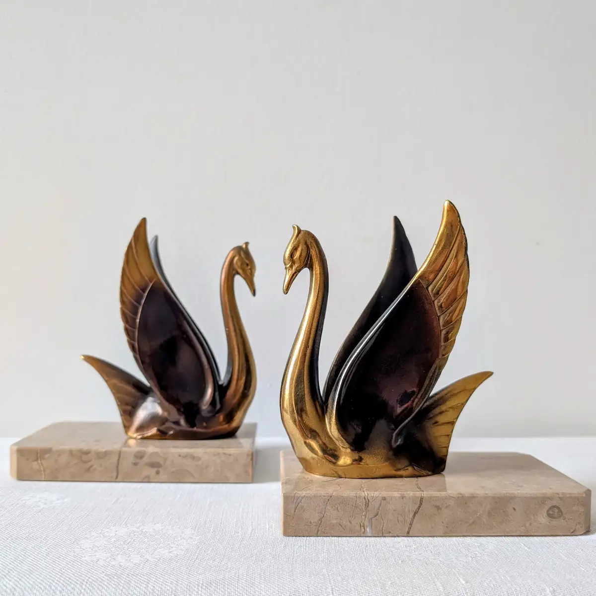 Vue de trois-quarts des serre-livres cygnes Art déco montrant la patine brune et dorée