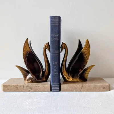 Paire de serre-livres anciens cygnes Art déco en métal doré encadrant un livre sur socle marbre