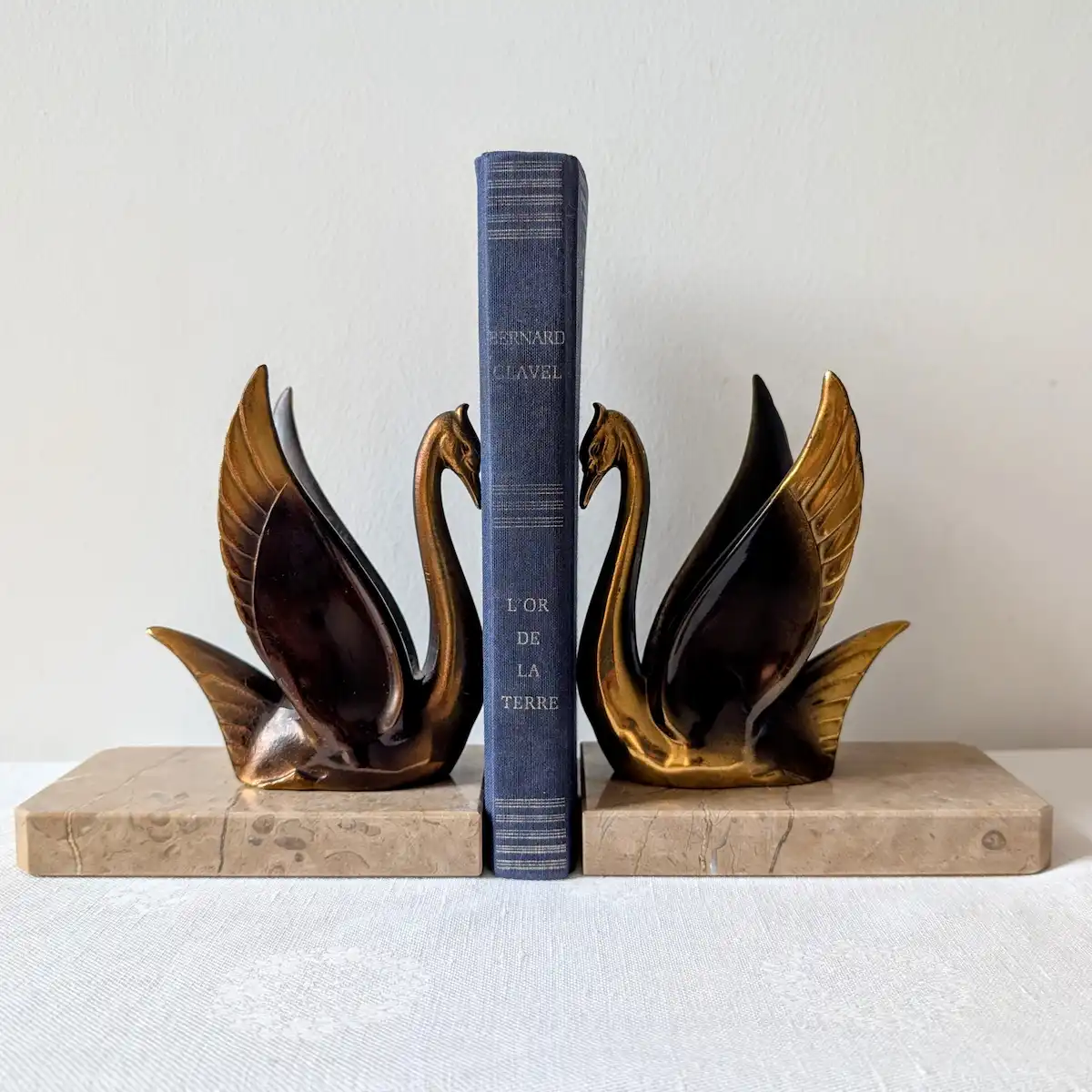 Paire de serre-livres anciens cygnes Art déco en métal doré encadrant un livre sur socle marbre