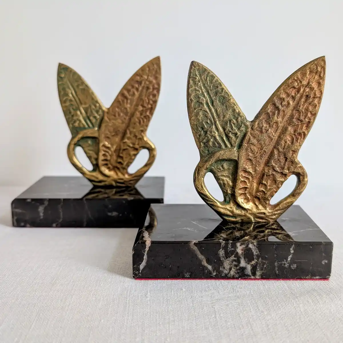 Vue de face des deux serre-livres vintage en marbre noir avec sculptures en forme de feuilles