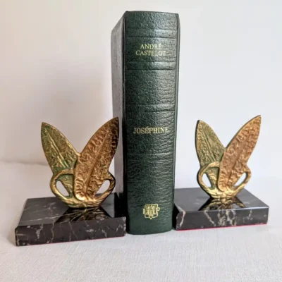 Paire de serre-livres vintage en marbre noir et métal doré retenant un livre relié