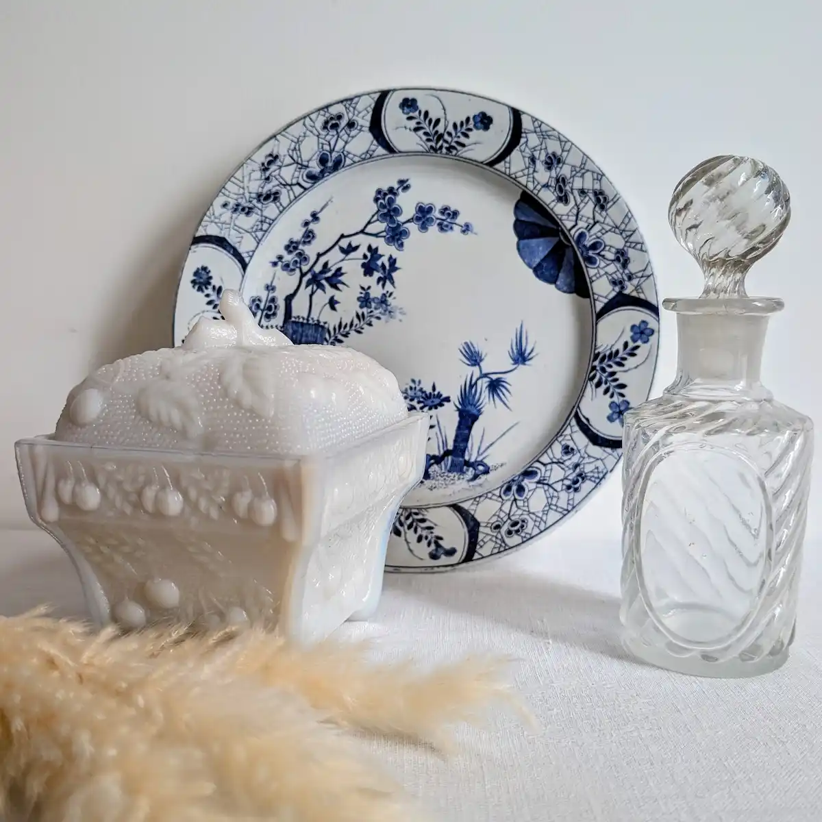 Composition décorative avec bonbonnière en opaline, faïence bleue et flacon en cristal
