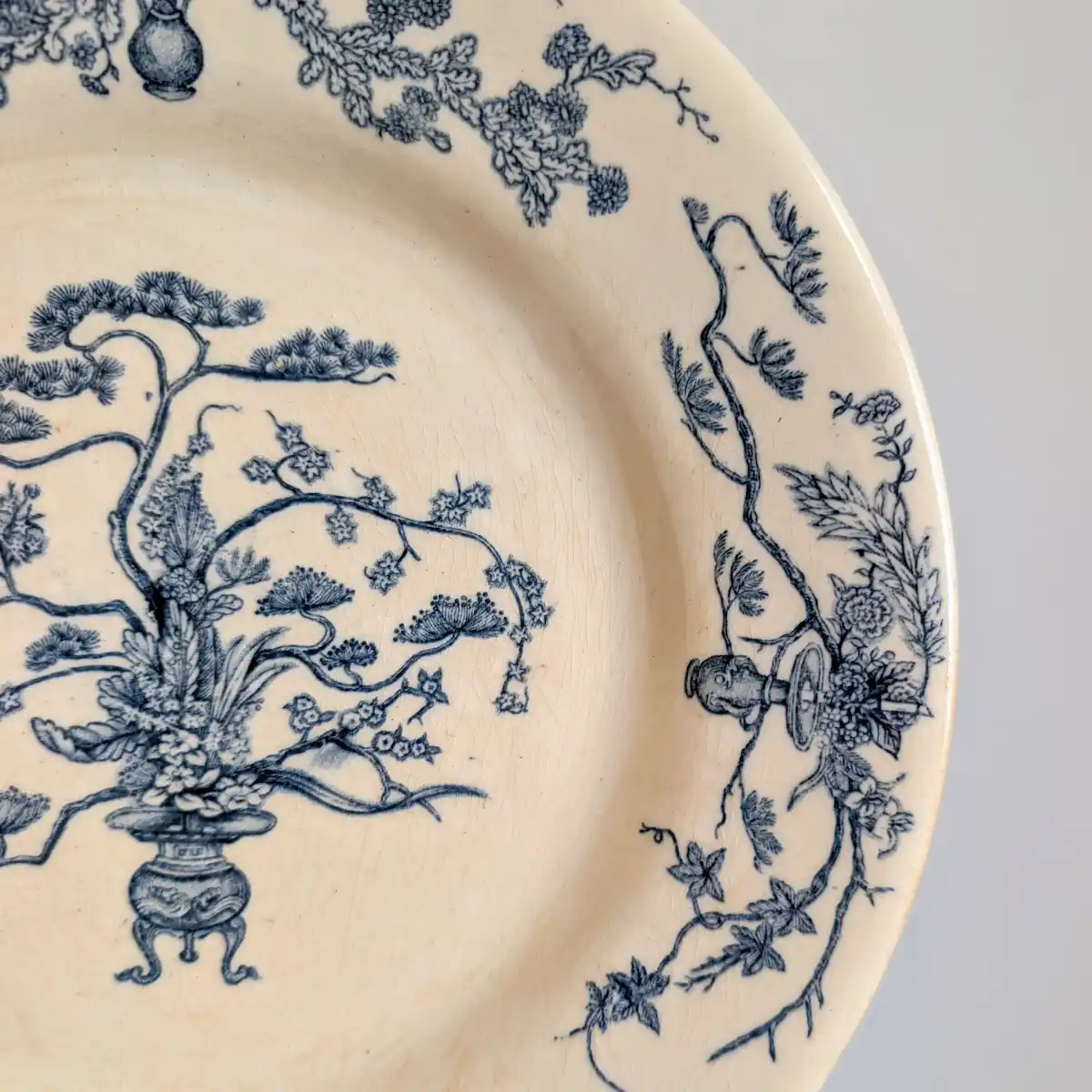 Détail de l'aile d'une assiette Gien ancienne avec frise florale bleue