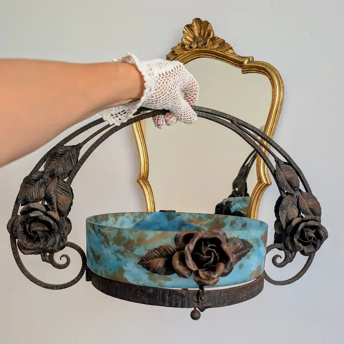 Présentation à la main en gants anciens d'une jardiniere en pâte de verre et fer forgé