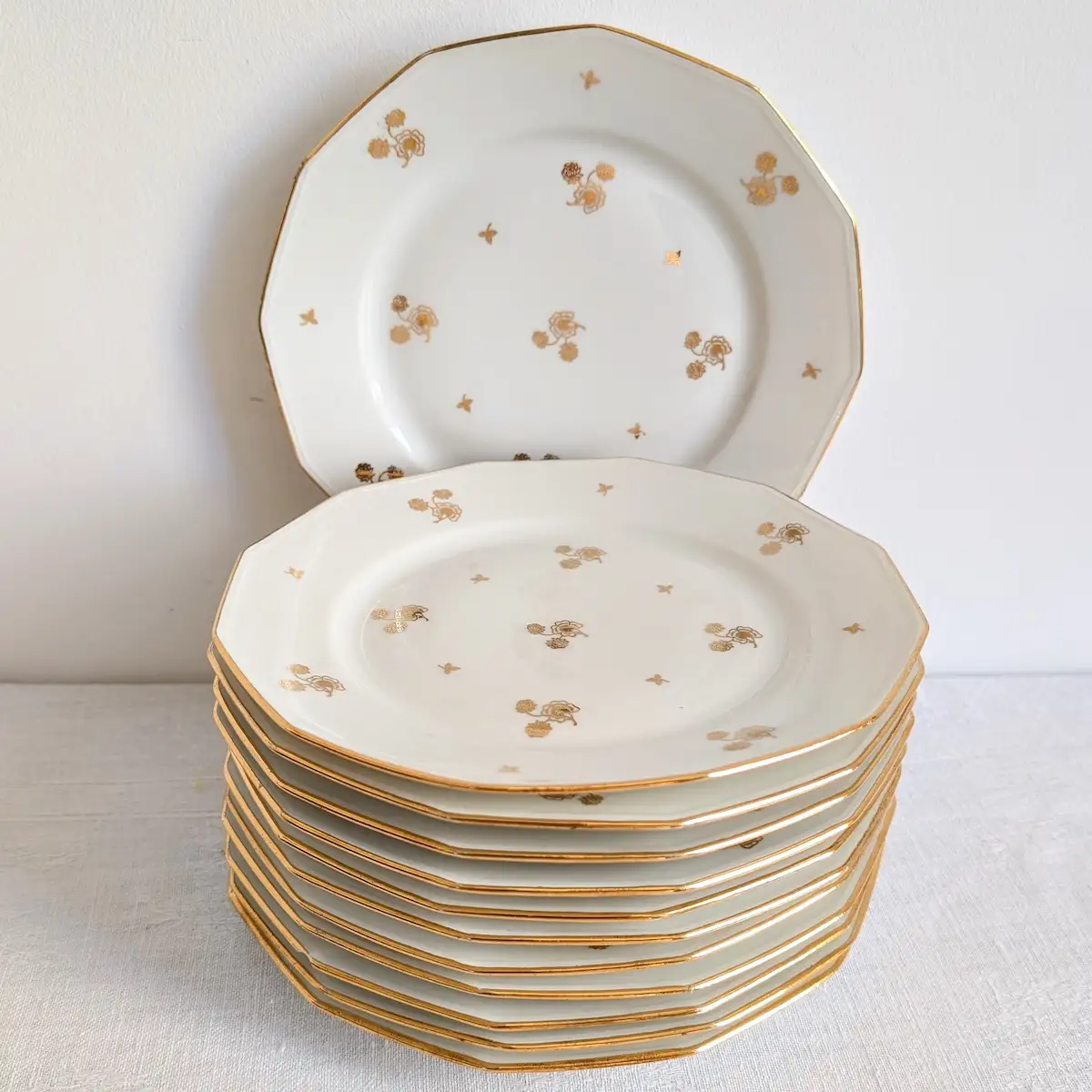 Empilement harmonieux des douze assiettes à dessert anciennes en porcelaine ivoire de Limoges