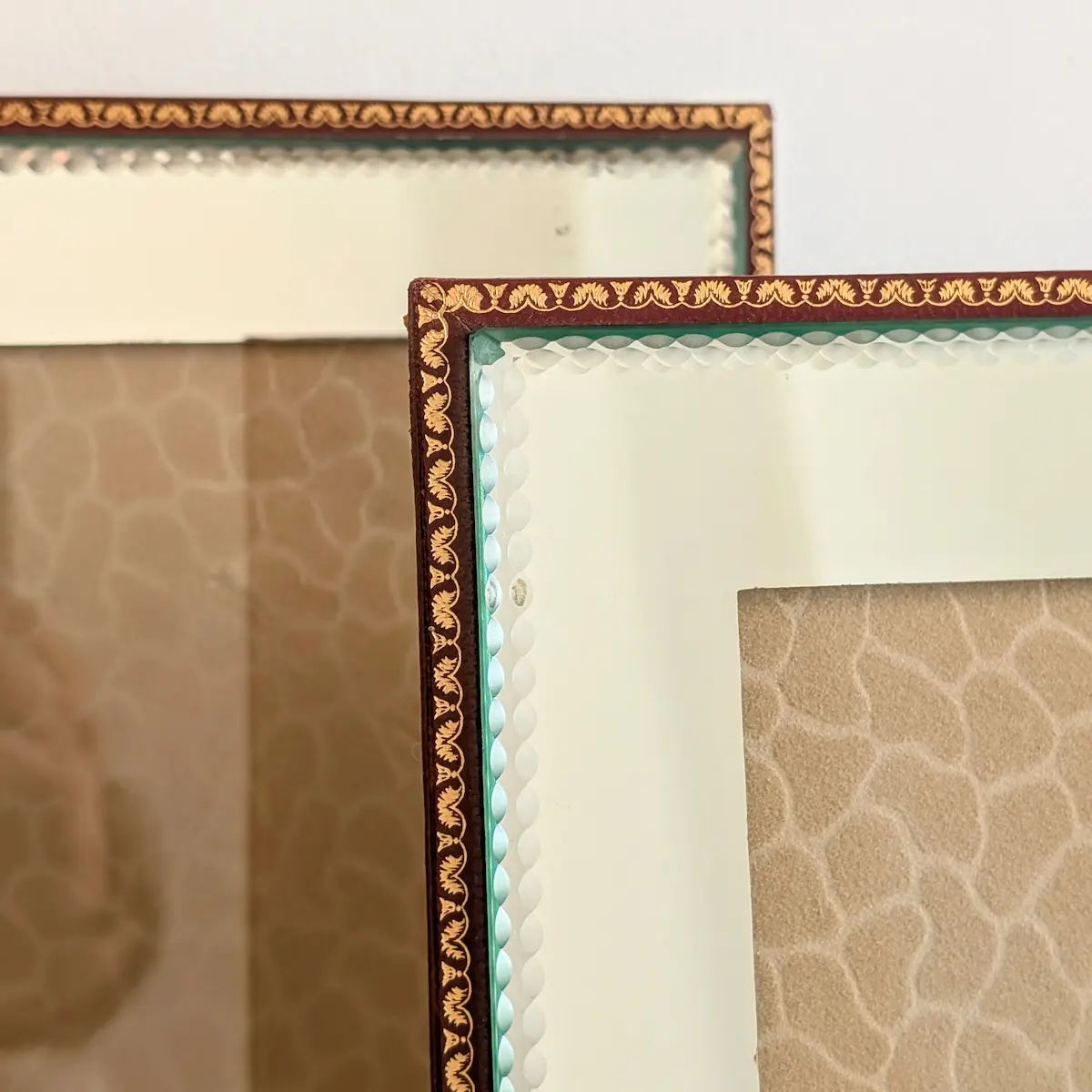 Détail de la frise végétale dorée sur simili-cuir bordeaux et biseautage du miroir