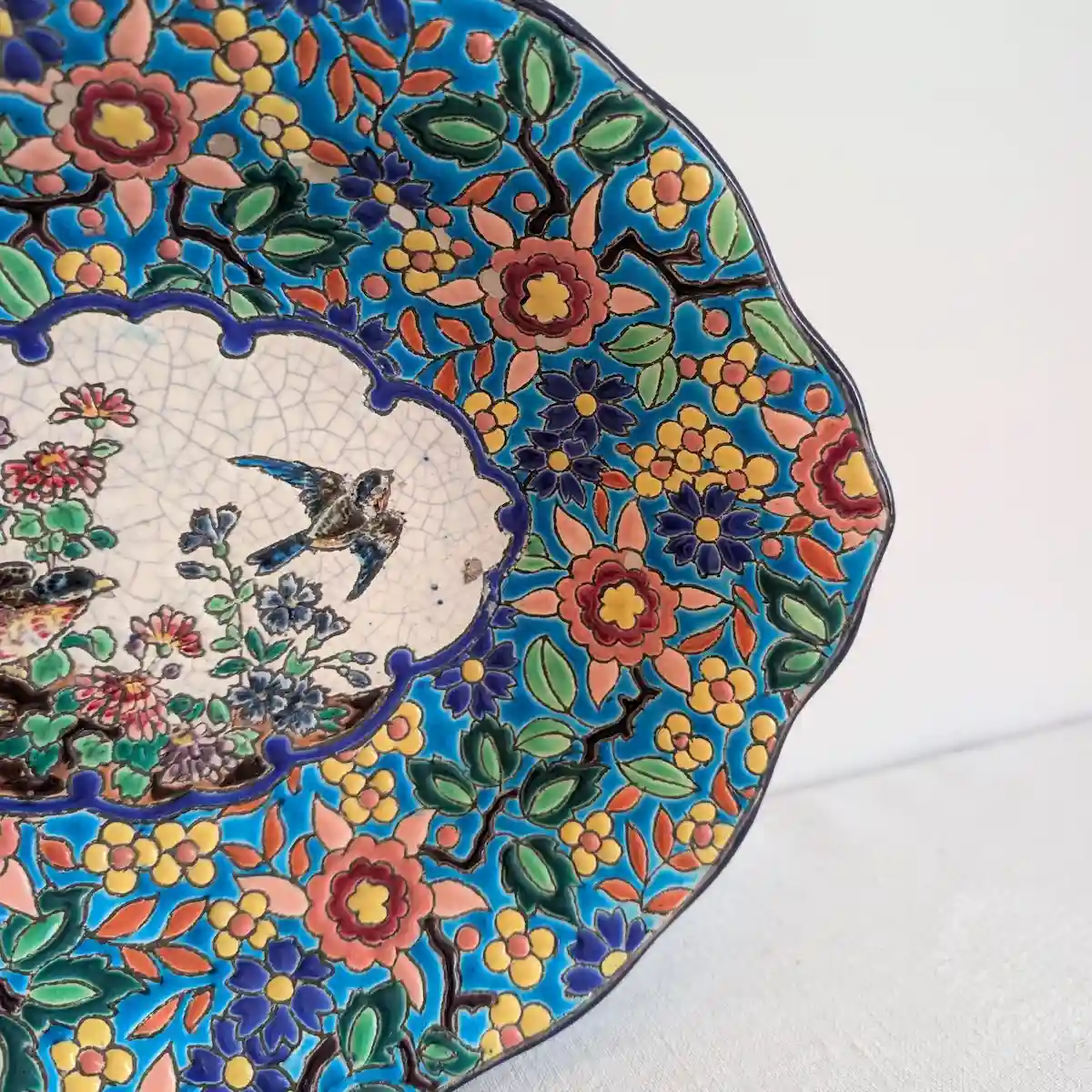 Détail des fleurs roses, jaunes et bleues et des feuilles vertes cernées sur fond turquoise