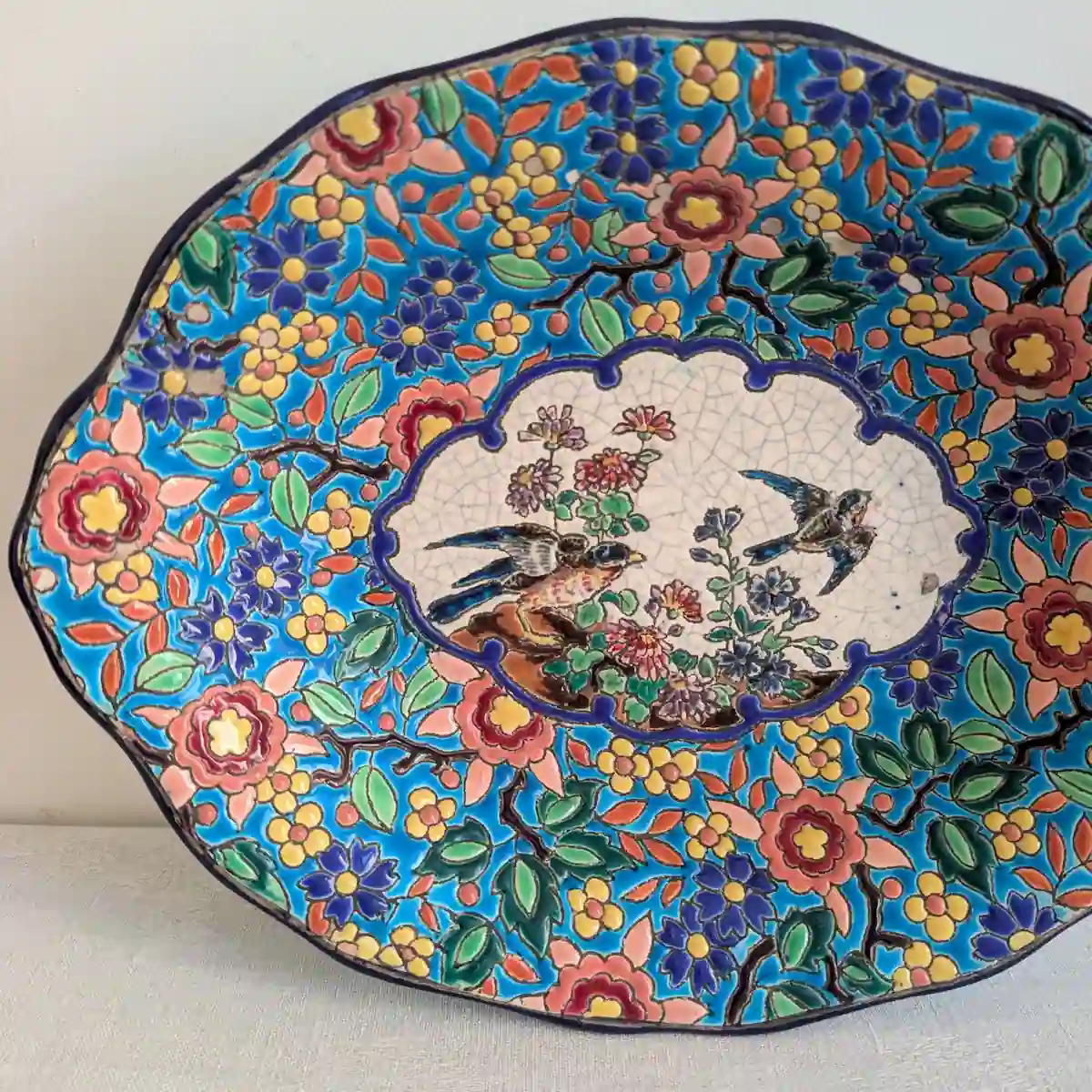 Vue rapprochée des deux oiseaux et des craquelures de la réserve crème du plat Longwy
