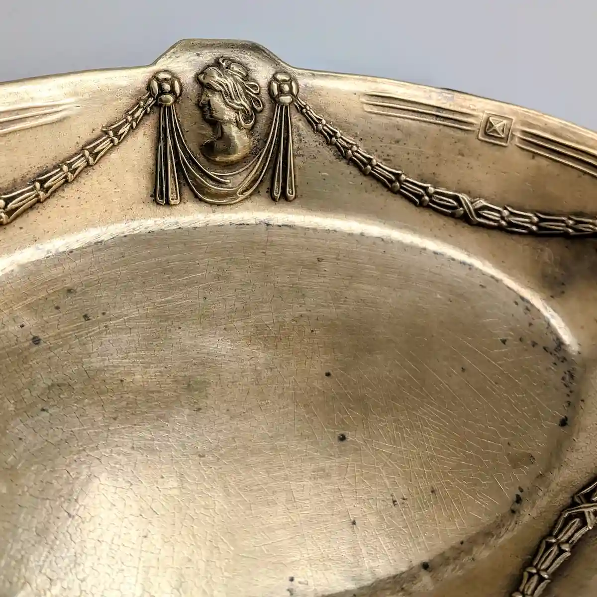 Gros plan sur le profil féminin à l'antique et les guirlandes en relief du plateau