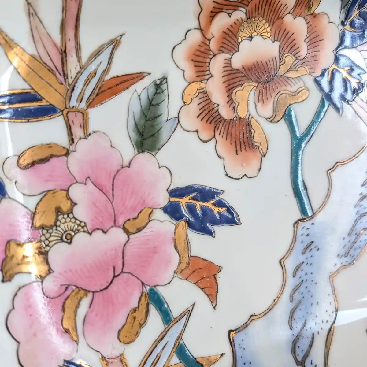 Gros plan sur les pivoines émaillées et les rehauts dorés du plateau en porcelaine.