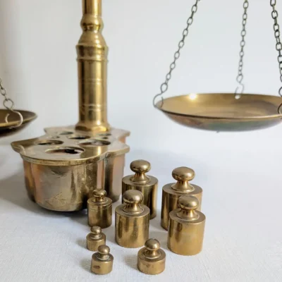 Ensemble de 8 poids en laiton de 10g à 200g disposés à côté de la balance ancienne