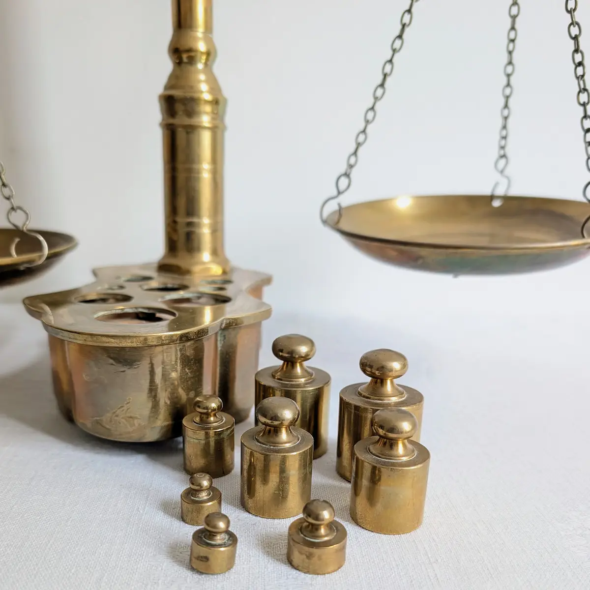 Ensemble de 8 poids en laiton de 10g à 200g disposés à côté de la balance ancienne