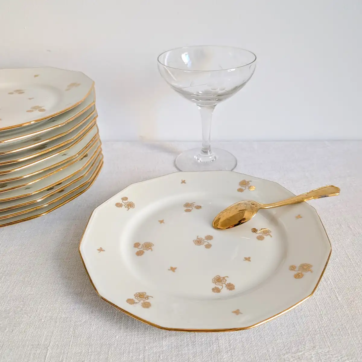 Série de douze assiettes anciennes de Limoges présentées avec vaisselle vintage et cuillère dorée
