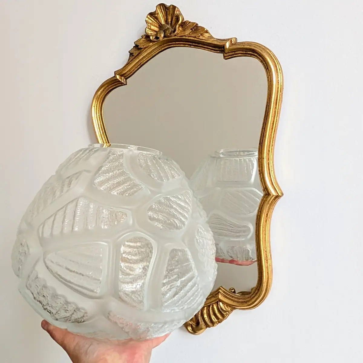 Vase boule ancien en verre présenté dans un intérieur décoratif aux côtés d'un miroir doré