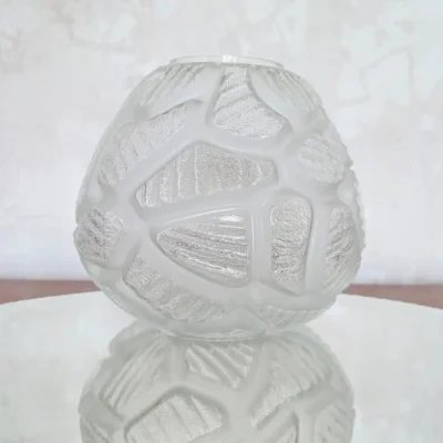 Vue de profil d'un vase ancien en verre texturé mettant en valeur ses reflets lumineux