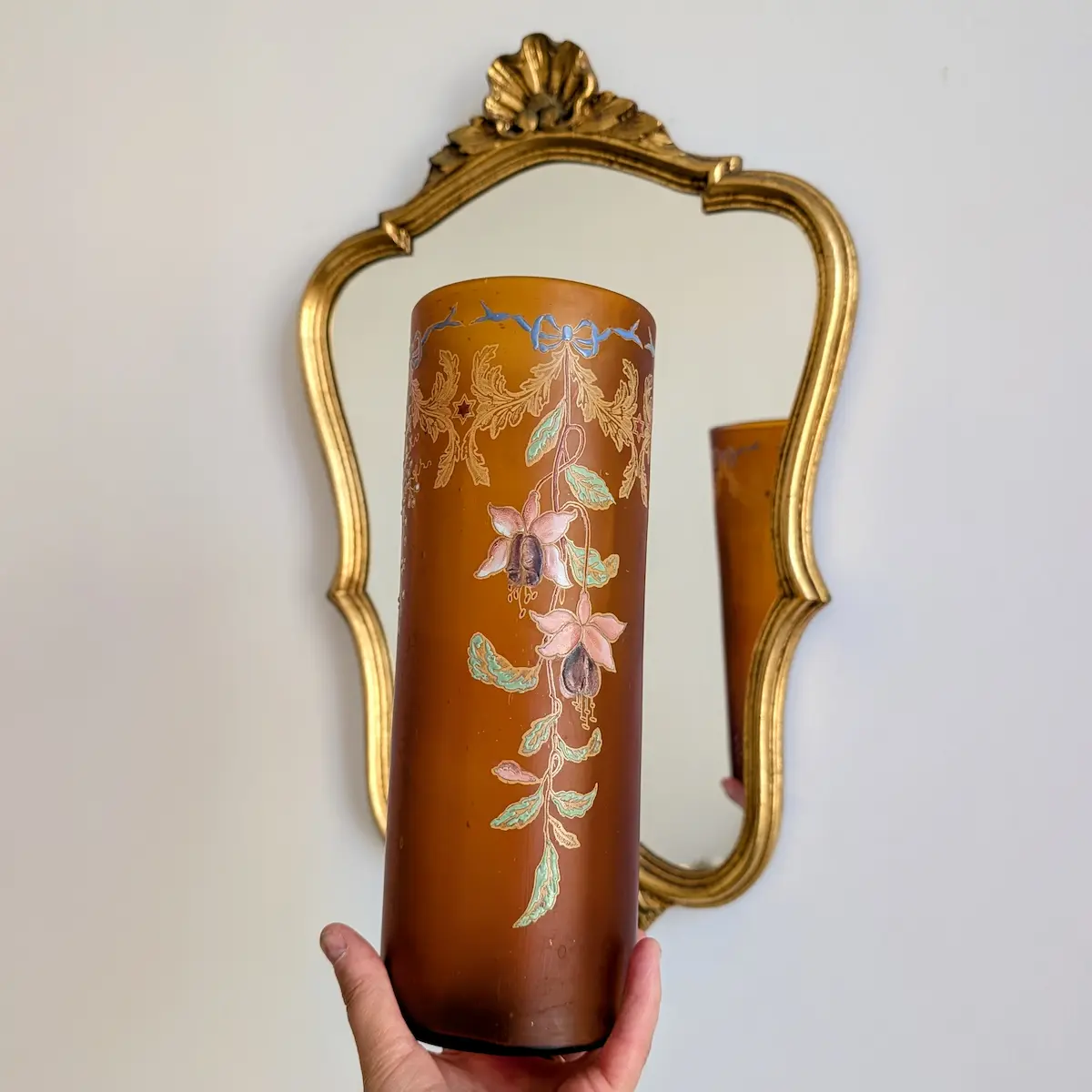 Vase art nouveau en verre ambré présenté devant un miroir ancien doré