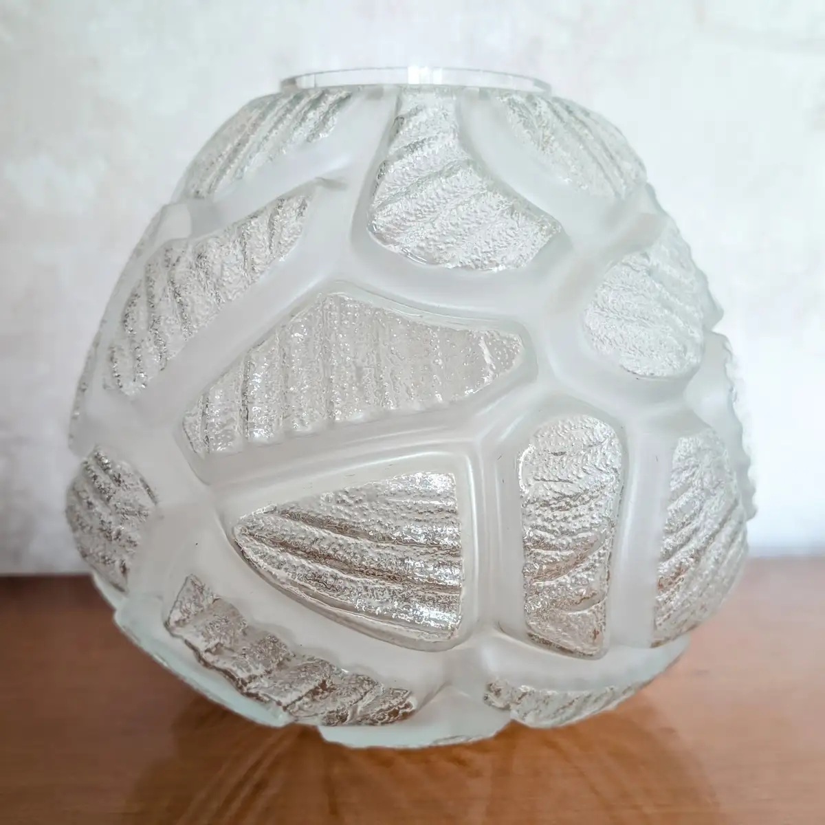 Détail rapproché des motifs géométriques en relief sur le verre d'un vase vintage