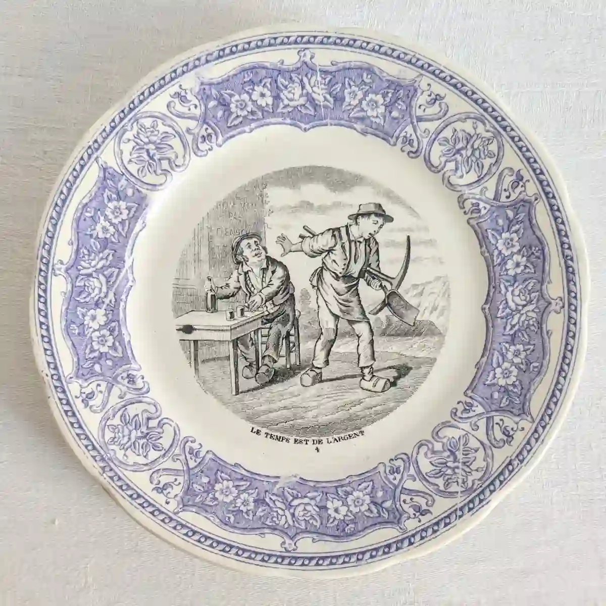 Assiette parlante numéro 4 représentant un travailleur avec une pioche près d'un homme assis à une table.