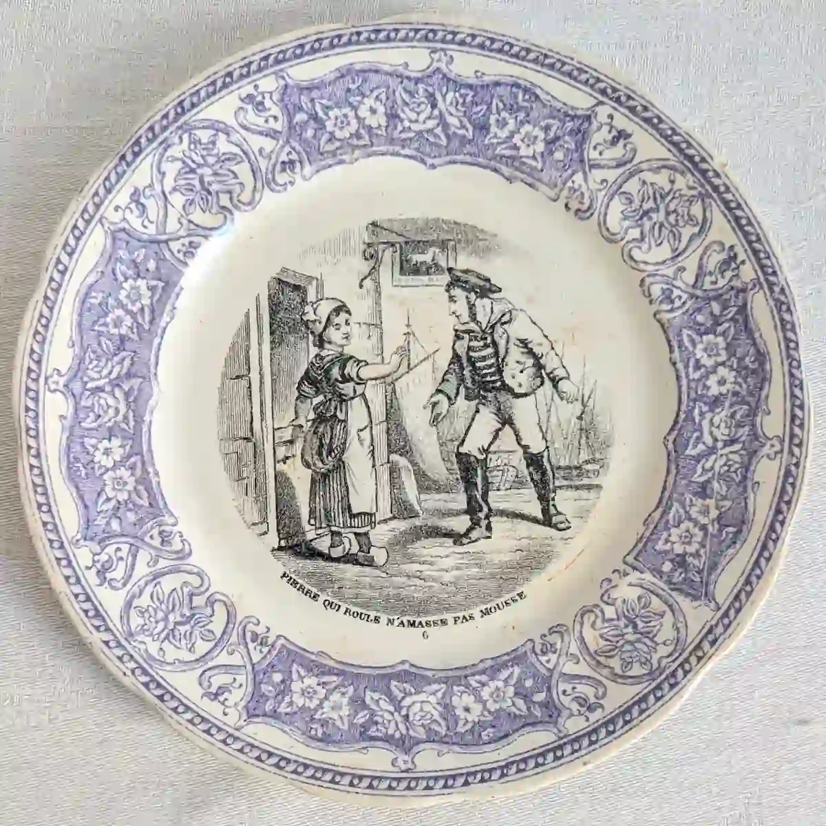 Assiette parlante numéro 6 illustrant une rencontre devant une maison pour le proverbe Pierre qui roule n'amasse pas mousse.