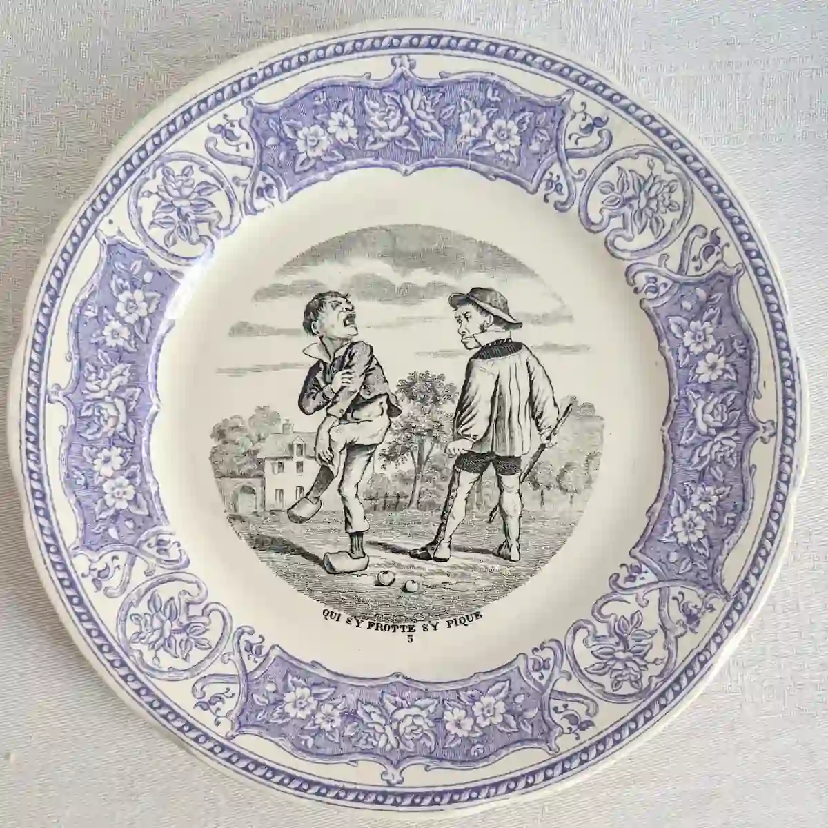 Assiette Digoin Sarreguemines numéro 5 avec deux garçons et des boules au sol, illustrant Qui s'y frotte s'y pique.