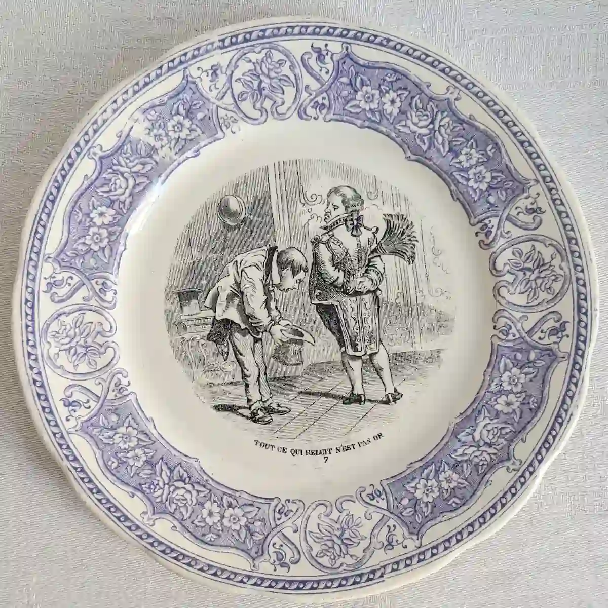 Assiette parlante numéro 7 représentant un homme courbé devant un personnage richement vêtu, sur fond de décor floral violet.