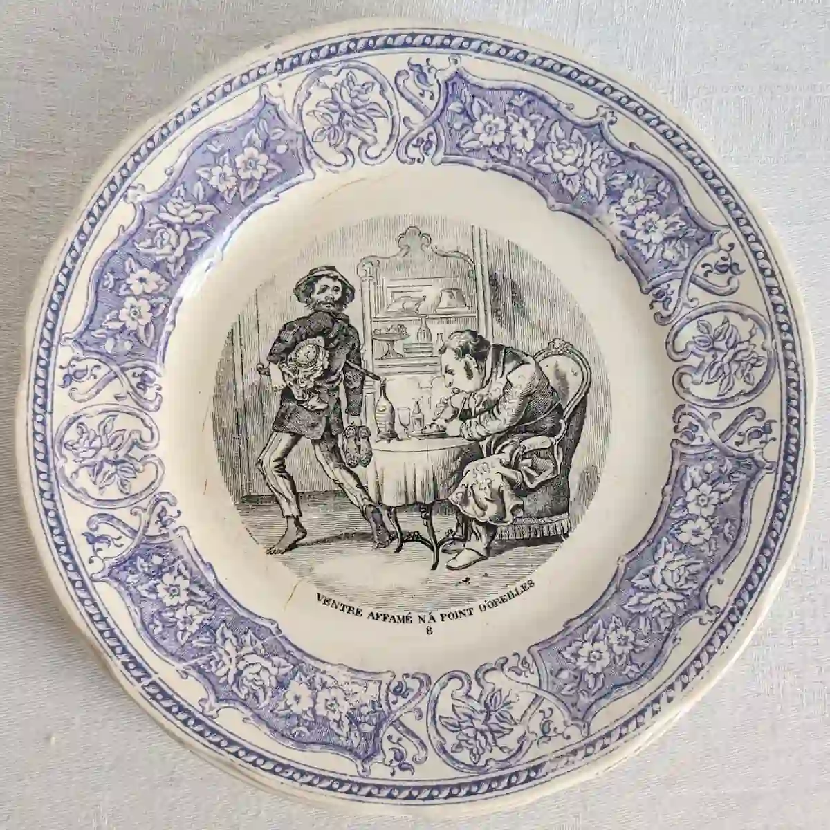Assiette ancienne numéro 8 montrant un personnage debout près d'un homme attablé, avec le proverbe Ventre affamé n'a point d'oreilles.