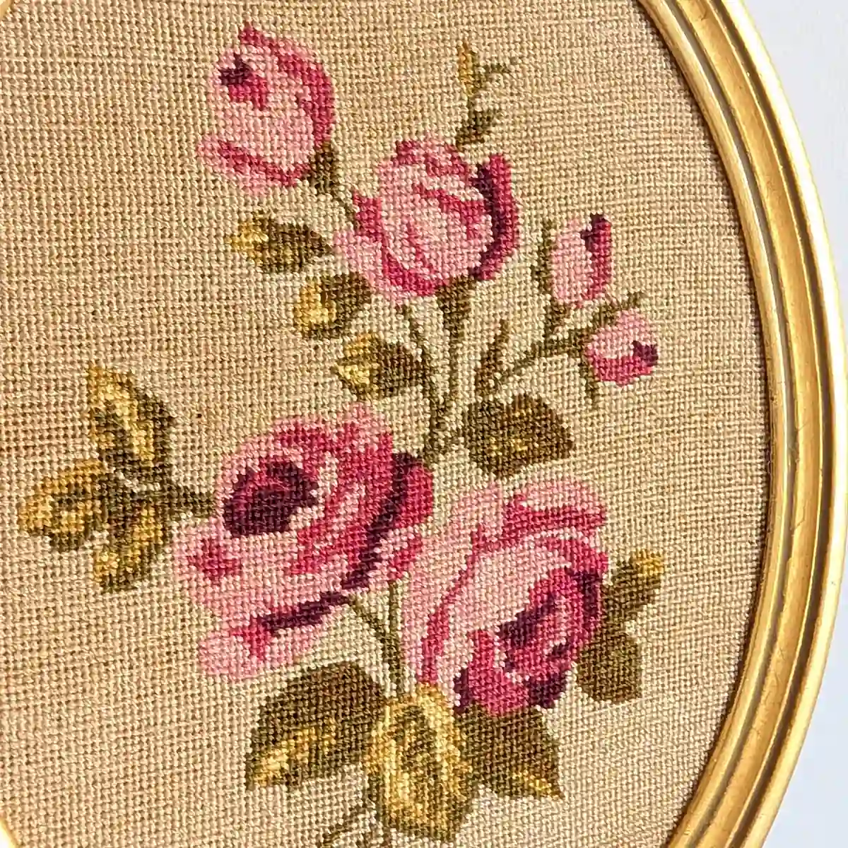 Gros plan des roses brodées rose poudré et framboise avec feuillage vert olive.