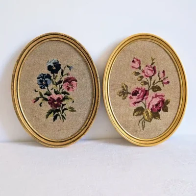 Deux cadres ovales dorés, avec pensées brodées à gauche et roses roses à droite.