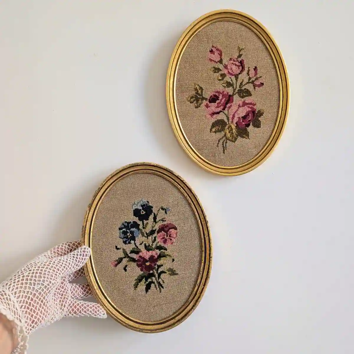 Cadres fleuris disposés en diagonale, roses en haut et pensées en bas, avec une main gantée.